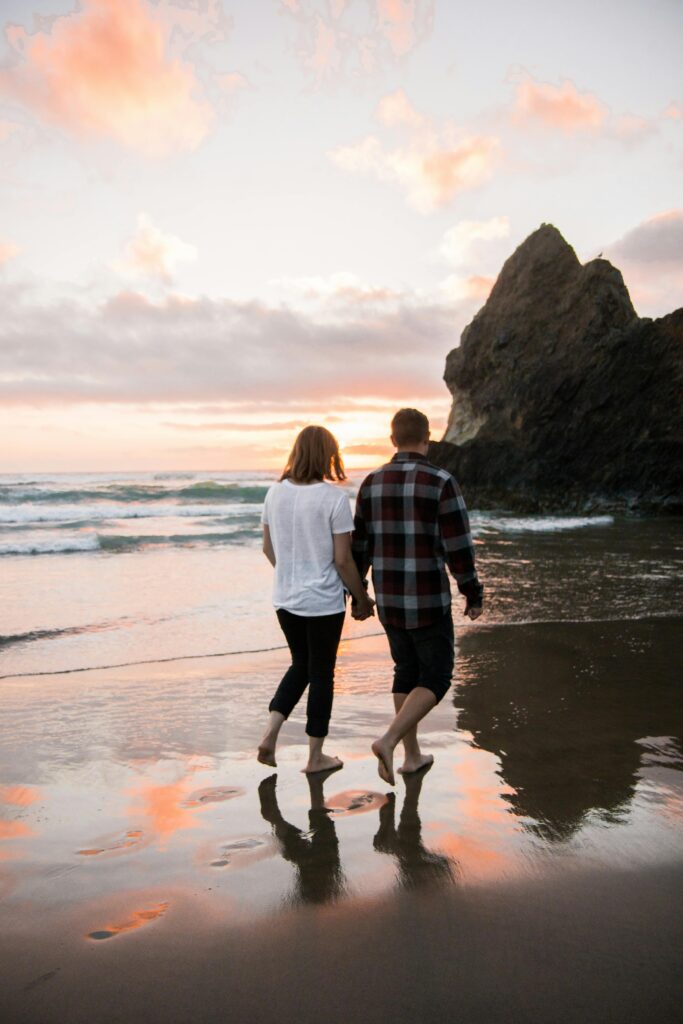 A couple walks hand in hand on the beach at sunset, reflecting serene love and tranquility.